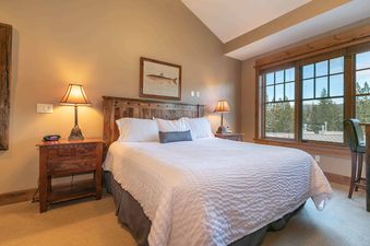 A bedroom with a large window showing a view of the mountains.