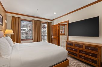 A spacious bedroom inside Ritz Carlton Club 3 Bedroom Penthouse 4302 features natural light, a king-sized bed, and a flat screen television.