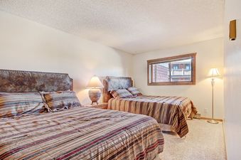 Two twin beds with striped bedding, a lamp on the nightstand and a tall floor lamp in the bedroom.