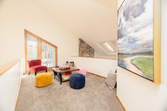A cozy play area at Snow Park Chalet with colorful poufs, a red accent chair, and a coffee table filled with board games, all illuminated by large triangular windows.
