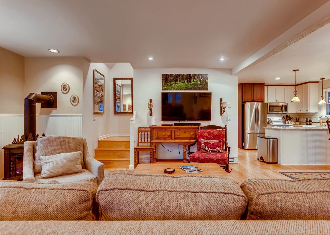 The living area of Chalet Montagne features a comfortable sofa and armchair, with a fireplace in the corner.