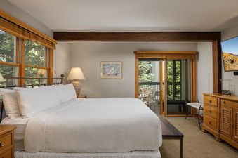 A cozy bedroom with a plush king bed and sliding glass doors leading to a scenic balcony.