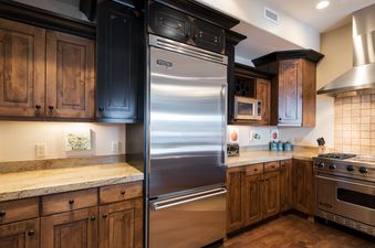 A gourmet kitchen at Silver Star 4202 featuring stainless steel Viking appliances, dark wood cabinetry, and light granite countertops.