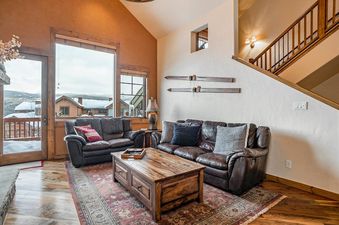 Cozy living room at Hygge Hideaway with leather sofas, wood coffee table, and snowy mountain views.