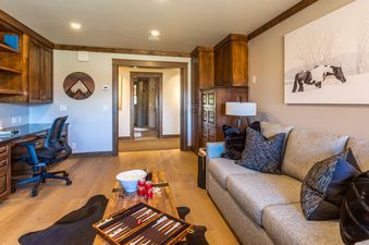 The home office area at Abode at Sage Springs includes a wooden desk, shelves, and a comfortable office chair.
