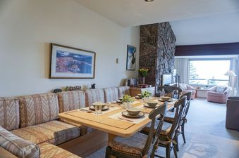 Dining area of Snowridge 2 with set table, seating, and a large stone fireplace.