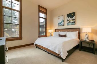 A bedroom with a king-sized bed, white linens, and two lamps on either side.
