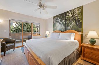 A master bedroom in St James Place 325 features a comfortable king-size bed with a wooden frame and a nature-themed mural above the headboard.