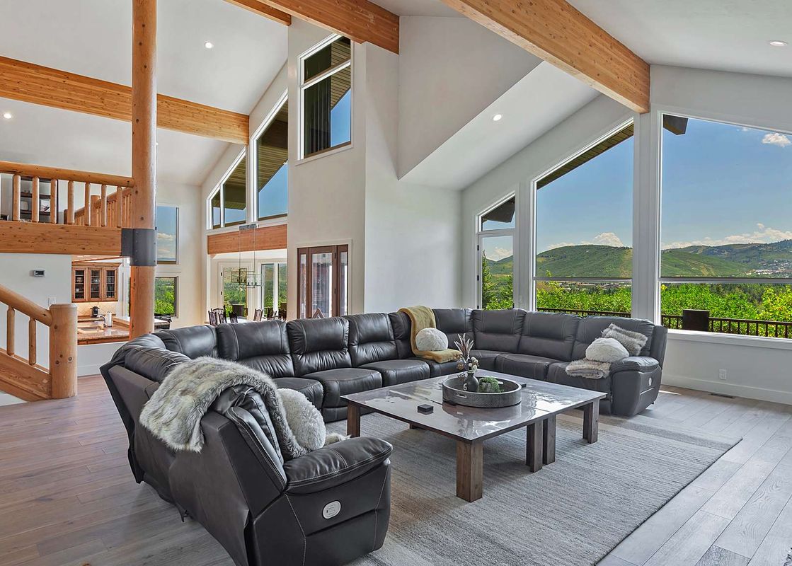 The luxurious living room at Timer Ridge Retreat features a large sectional sofa, a coffee table, and an incredible view of the mountains from the expansive windows.