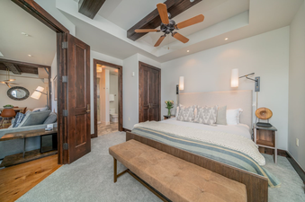 The bedroom in Lumiere One Bedroom Deluxe Residence has a king bed, a bench at the foot of the bed, and a dresser beside the bed.