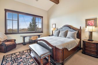 A king bedroom at Silver Star 47 with rich wooden furniture and a large window showcasing mountain views.