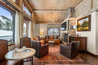 The beautifully decorated living room in Ritz Carlton Club 3 Bedroom Penthouse 4302 features a stone fireplace and views of the slopes.