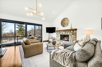 The luxurious living room in Deer Valley Solamere Home features comfortable seating and a stone fireplace.
