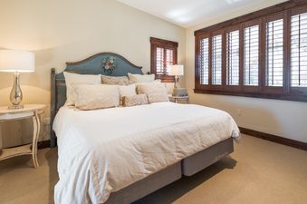 A cozy bedroom at Silver Star 39 features a bed with a painted blue headboard, bedside tables with lamps, and wooden-shuttered windows.