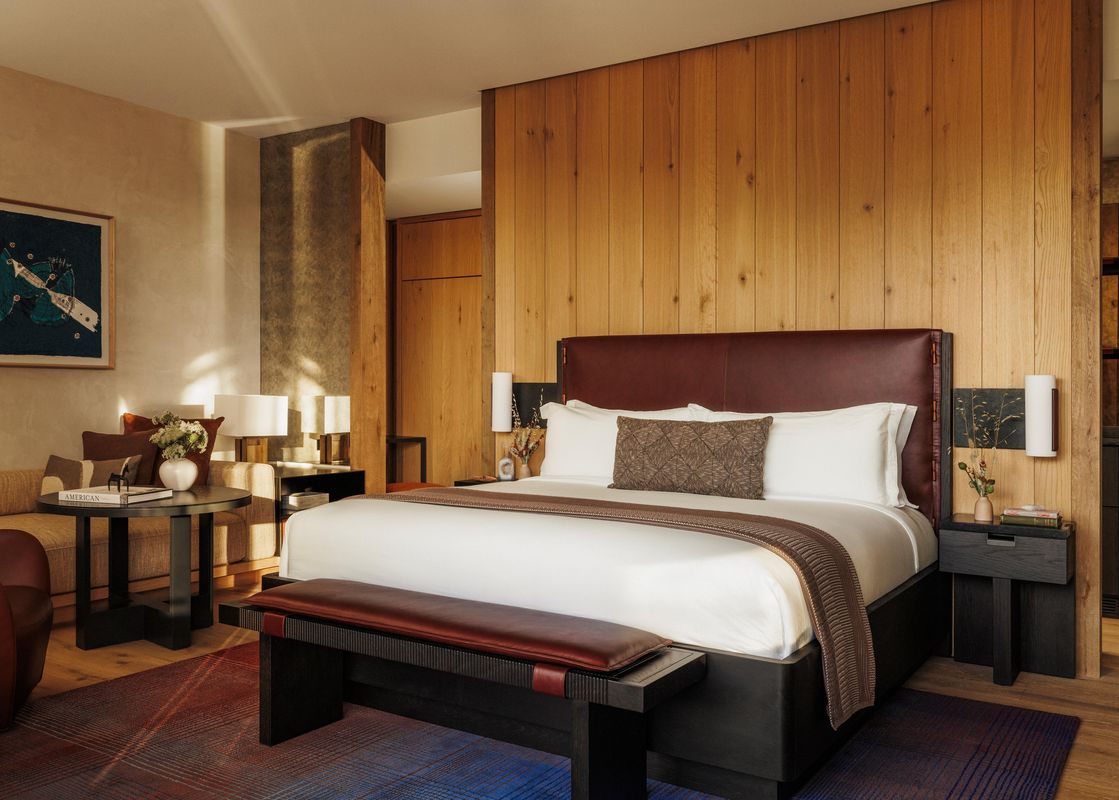 A luxurious bedroom in the Moonlight Room with a king bed, leather headboard, wood-paneled wall, and a cozy seating area in the background.
