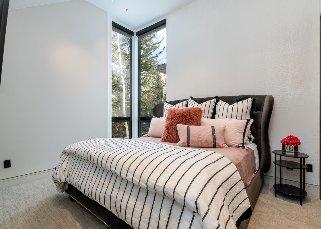 Chic modern bedroom at La Foret on Forest Road with a striped duvet and corner windows.