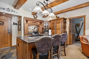 A kitchen with wood cabinets and a breakfast bar with stools.