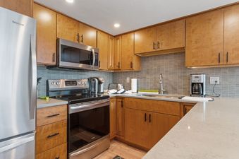 A kitchen with stainless steel appliances, wooden cabinets, and a gray countertop.