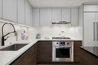 Modern kitchen with stainless steel appliances, white cabinets, and a black faucet.