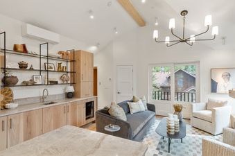 A modern living area in Depot House with a wet bar, comfortable seating, and large glass doors opening to an exterior view.