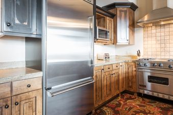 A gourmet kitchen at Silver Star 3302 featuring stainless steel appliances, wood cabinetry, granite countertops, and a patterned rug.