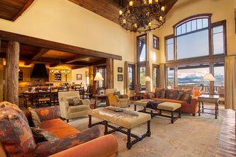 The grand living room features high ceilings, a large chandelier, and expansive windows showcasing mountain views.