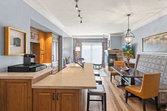 The open-concept living area features a kitchen island, a dining table, and a cozy fireplace, all bathed in natural light.