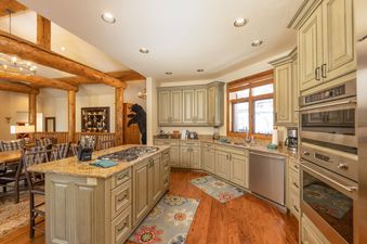 A rustic-themed kitchen at Beavers Lodge at River Ridge features light green cabinetry, granite countertops, and stainless steel appliances.