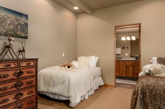 Moonlight Basin 2 Mountain Home bedroom features two beds, a dresser, and soft plush bedding.