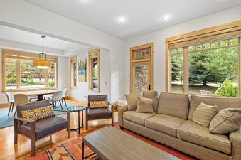 A spacious and modern living and dining area in Elevation 6000 Condo Unit 99 1, featuring comfortable seating, a stylish dining set, and large windows with outdoor views.