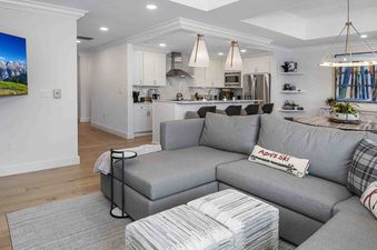 A modern open-concept living and dining area in Ritz Carlton Vail 314 with a grey sectional sofa, a dining table, and a contemporary kitchen.