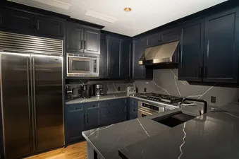 Modern kitchen with stainless steel appliances and dark cabinetry.