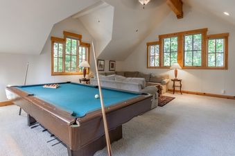 A spacious entertainment loft at the Northstar Sierra Gold Home features a billiards table and comfortable seating under vaulted ceilings with large windows.