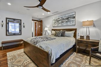 A beautifully furnished master bedroom with a large bed, abstract art, and a decorative mirror, offering a luxurious and comfortable stay.