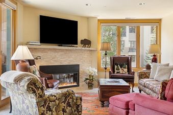 Inviting living room at 411 Beaver Creek Lodge featuring a stone fireplace, flat-screen TV, and cozy armchair seating.