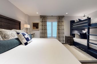 The comfortable bedroom in Chateau Christian 2 Bedroom Diamond Unit 120 features a large bed and a bunk bed, creating a versatile sleeping arrangement.