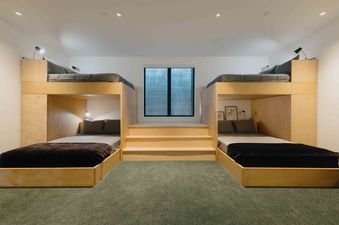 A bedroom with two sets of bunk beds, a large window, and a green carpet.