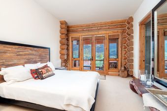 The primary bedroom at Townhomes on the Creek 117 with log walls and mountain views.