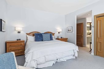A serene bedroom at Highlands Slopeside 222 featuring a queen-sized bed with white linens, blue pillows, wooden nightstands, and wall-mounted lamps.