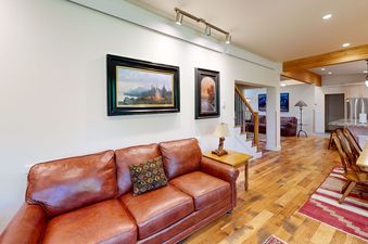 An inviting open-concept living and dining area in Eagles Rest 5 featuring a brown leather sofa, hardwood floors, and a glimpse of the kitchen.
