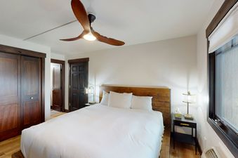 The bedroom in Phoenix 107 features a comfortable bed with white linens, a wooden headboard, and a ceiling fan.