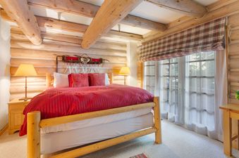 Pine Inn 3 features a rustic, cozy bedroom with a king bed, a wood-burning fireplace, and large windows that offer stunning views of the mountains.