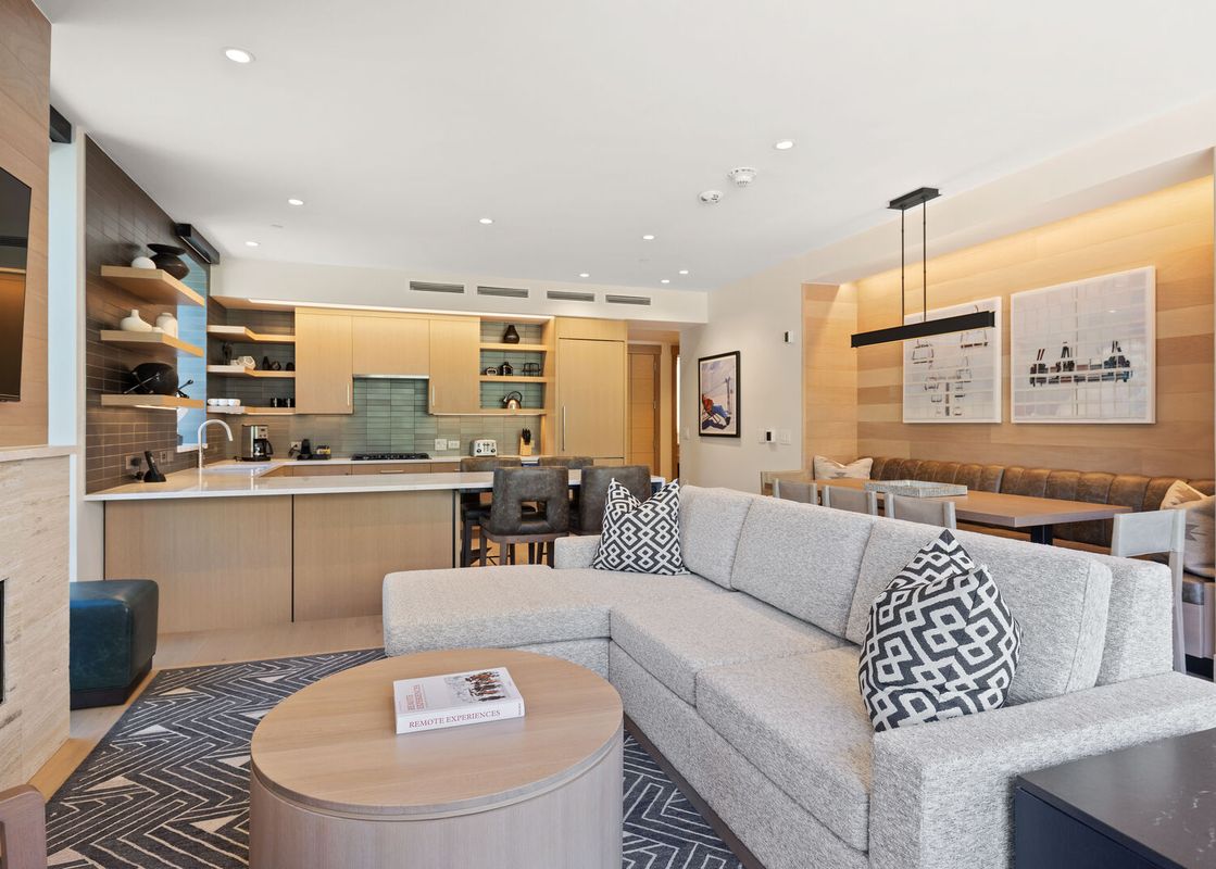 An inviting open-concept living area in Assay Hill Lodge Unit 264 features a modern kitchen, dining nook, and a comfortable lounge with a fireplace.