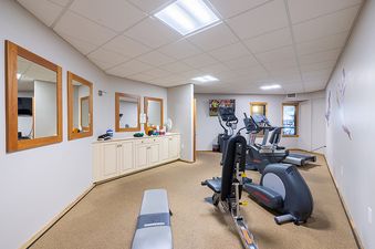 A small gym with various exercise equipment including treadmills and ellipticals