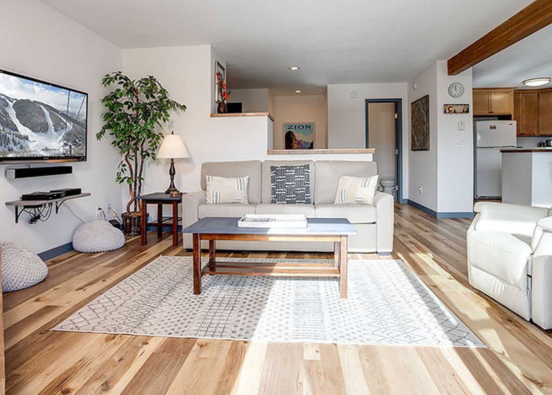A bright living room in the Ranch at Steamboat RA215 with a sofa, coffee table, and a TV, seamlessly flowing into a kitchen area.