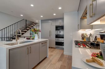 The modern kitchen in Abode on Cloud 9 boasts stainless steel appliances, light gray cabinets, and a large island.