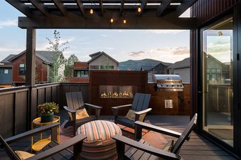 Modern outdoor balcony at Konik Chalet featuring a built-in fireplace, BBQ grill, and cozy seating area under a pergola.