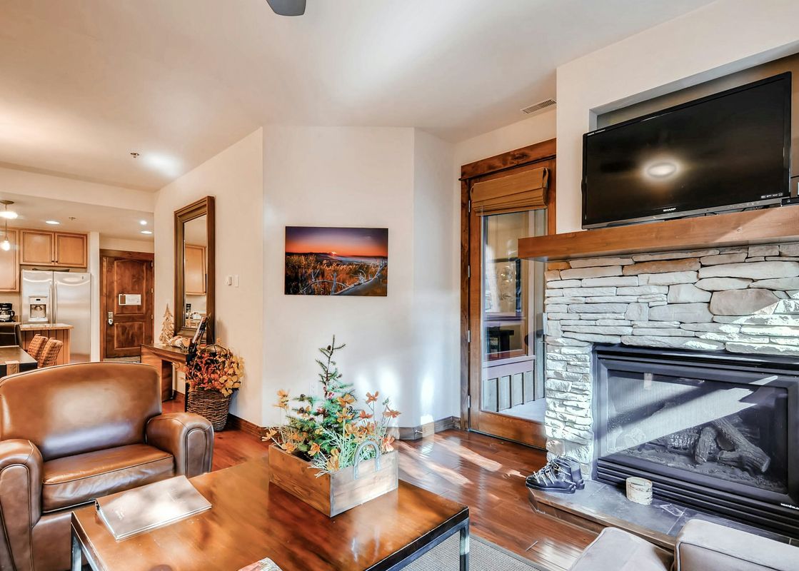 A living room with a fireplace, a leather armchair, a wooden coffee table, and a picture on the wall.
