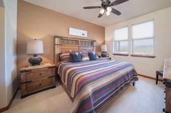 The bedroom in Cozen Pointe I201 features a wooden bed frame, two nightstands with lamps, a colorful striped comforter, and a ceiling fan.