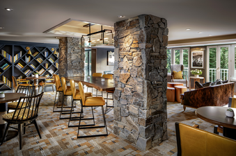 A cozy lounge area in the Fairmont Chateau Gold King Room with comfortable seating, a long communal table, and a bookshelf filled with books.